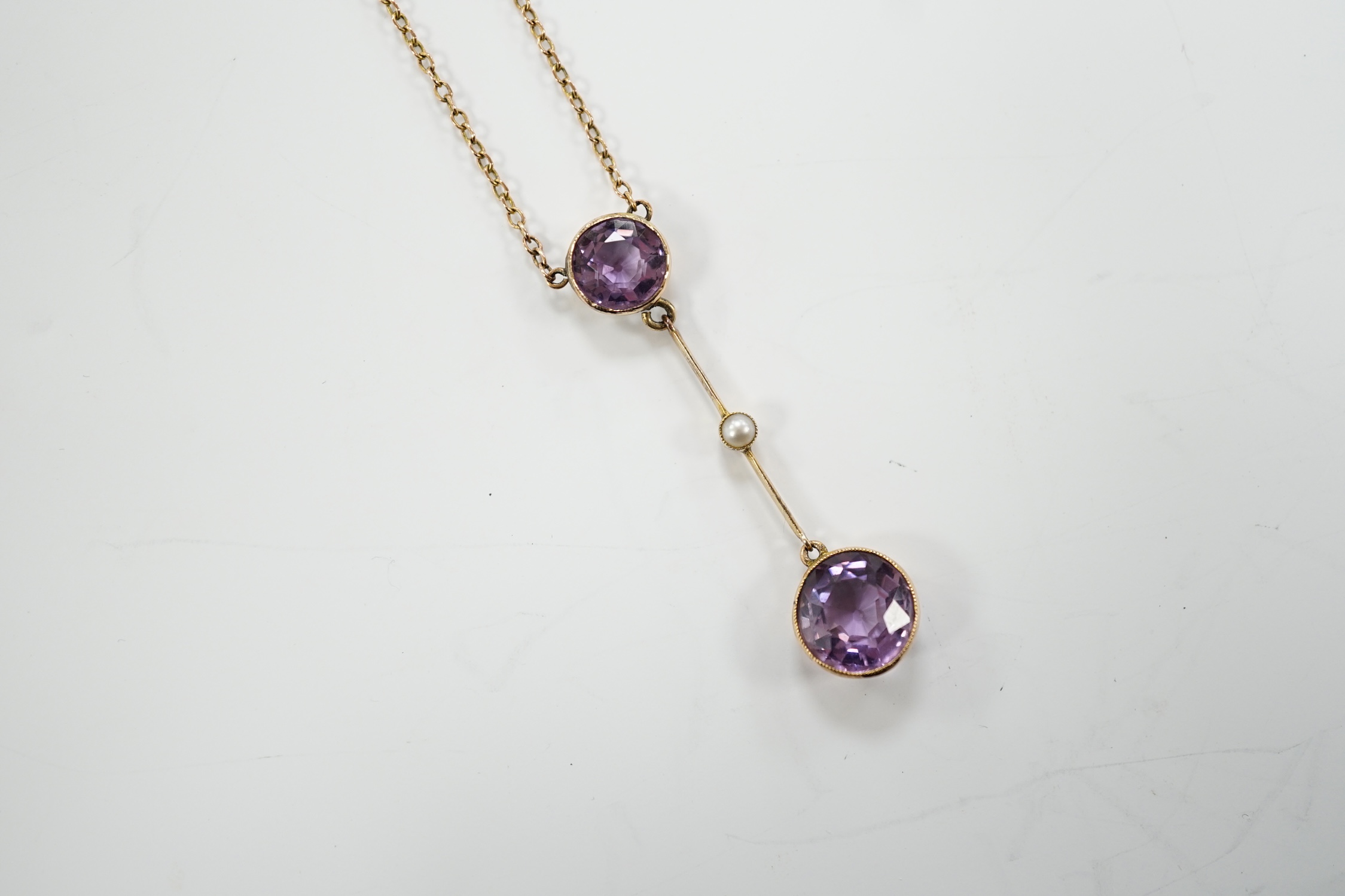 An Edwardian 9ct, two stone amethyst and single stone seed pearl set drop pendant necklace, gross weight 3.8 grams.